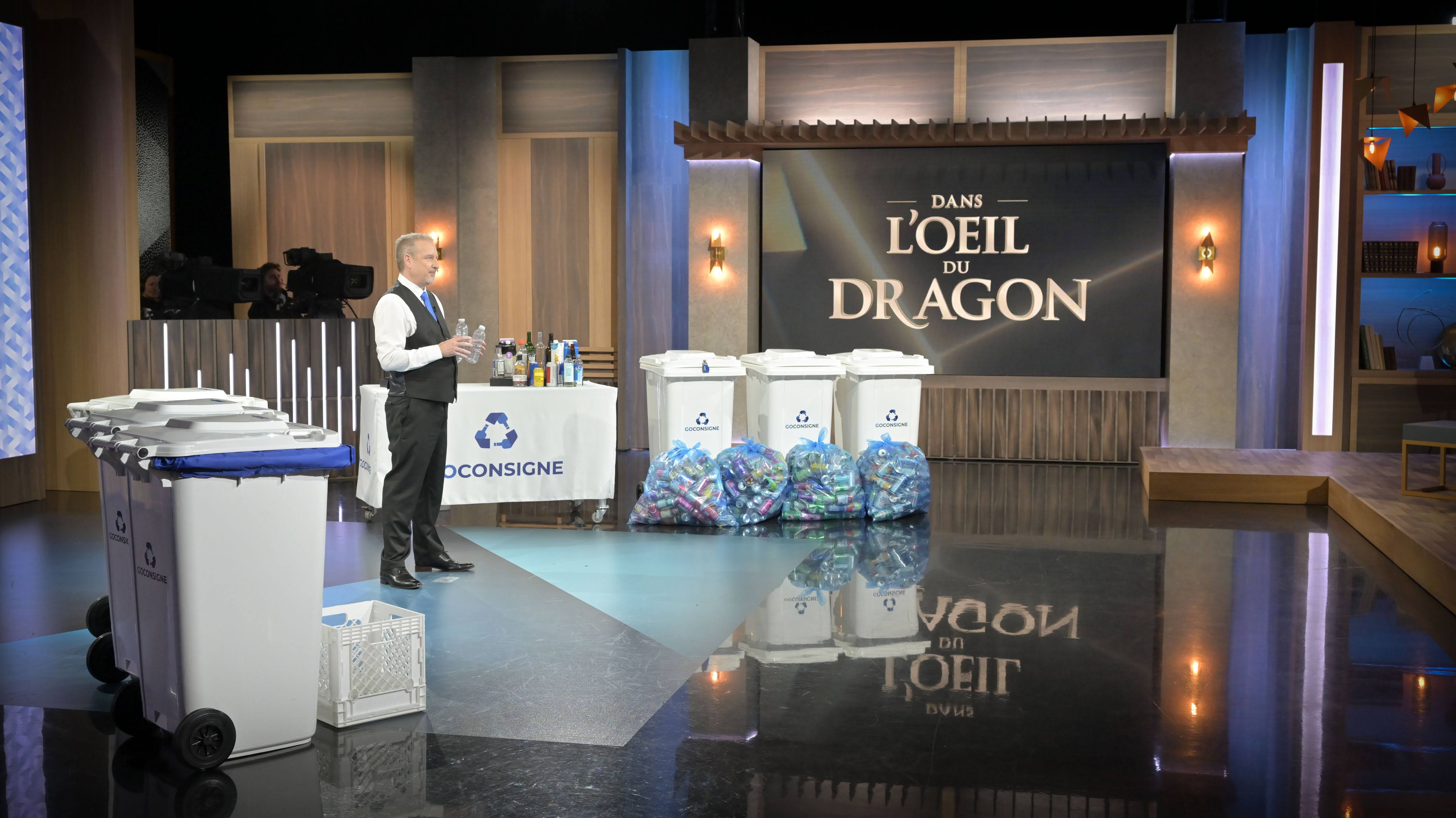 Un homme devant des contenants consignés présentant son entreprise Go Consigne à l'émission Dans l'oeil du dragon